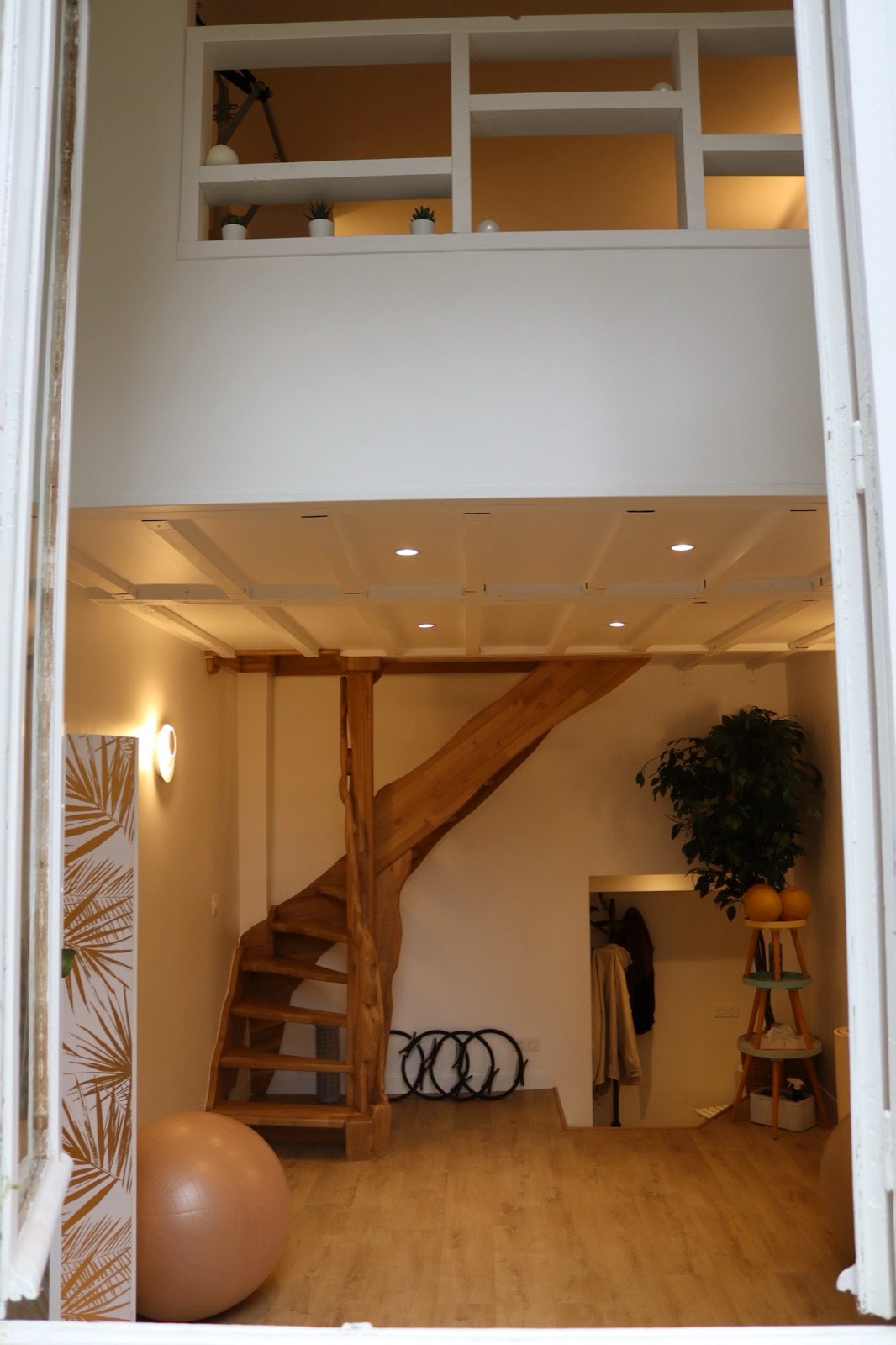 Le studio, vu depuis l'entrée : le plancher clair, la mezzanine et la poutre en bois.